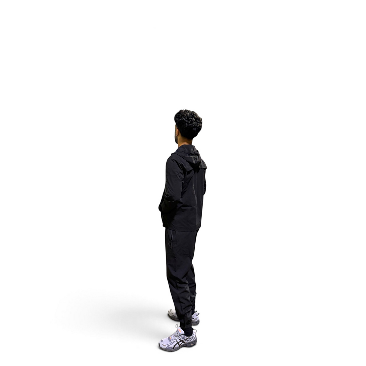 A person shown from the back wearing a black hooded jacket and black pants, standing against a plain white background.